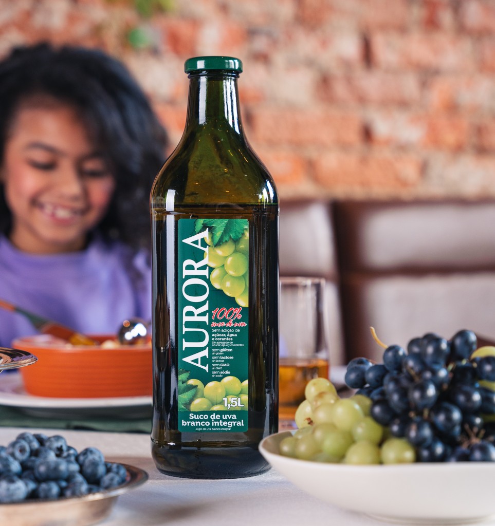 criança na mesa comendo e tomando um suco de uva da aurora