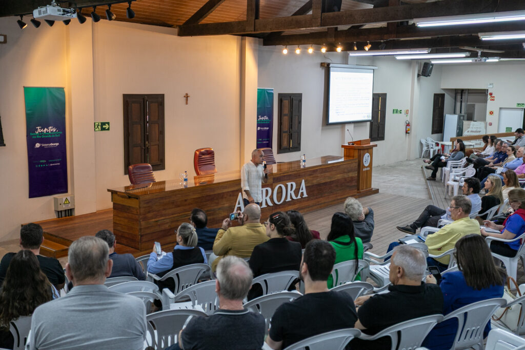 Palestrante fala ao público em auditório da Cooperativa Vinícola Aurora.