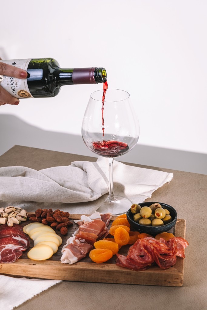 vinho tinto aurora marcus james cabernet sauvignon sendo servido acompanhado de tabua de frios