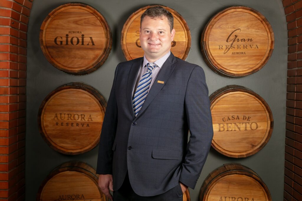 Homem de terno em frente a barris de vinho personalizados.