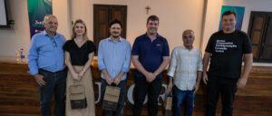 Seis pessoas posam para foto após evento na Cooperativa Vinícola Aurora.